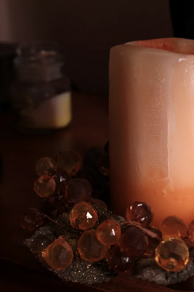 A rough-cast pillar candle on amber glass beads